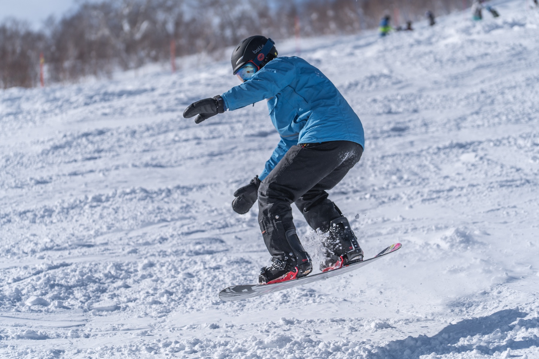 Snowboarder carving down a bright snowy slope