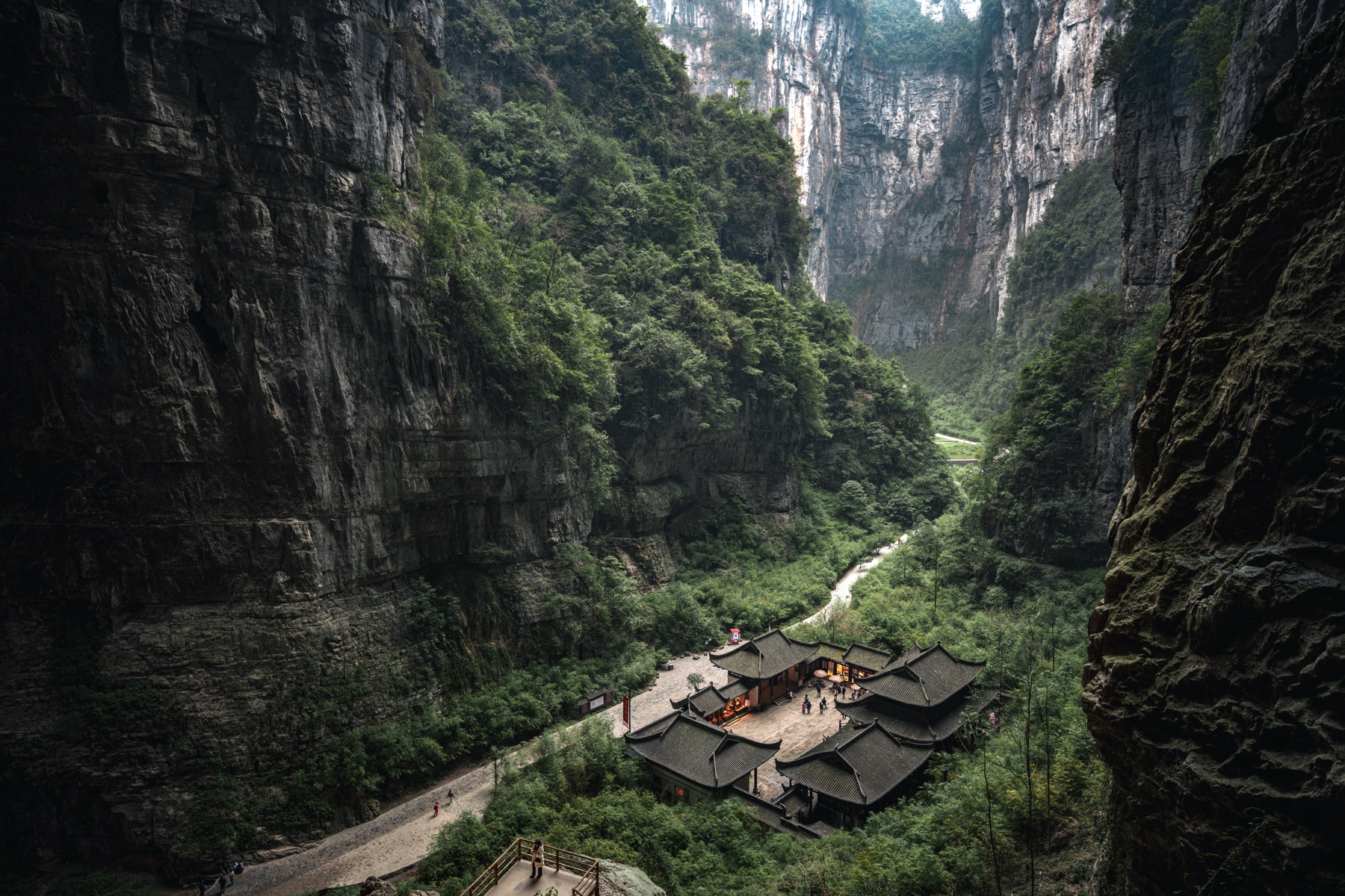 Wide canyon landscape with cliffs, greenery, and buildings below
