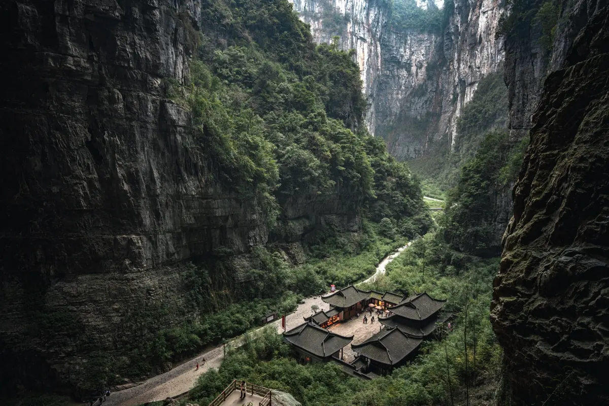 Wide canyon landscape with cliffs, greenery, and buildings below